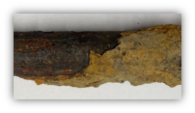 Image of oxidized galvanized iron pipe. The pipe is dark and orange (rusted-looking).